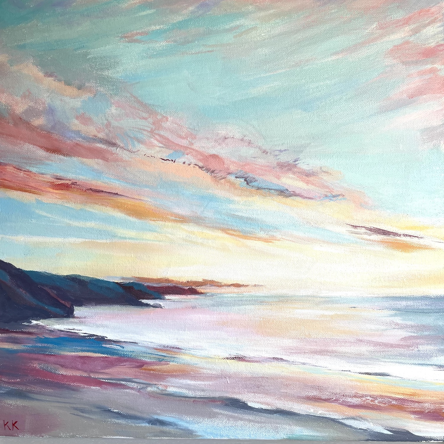 The beach angles down to the right hand corner dark pink, sandy yellow and pale ble. The dark blue headland is along the horizon line sitting on the left hand side of the painting. The distant sky is above full of pink trails and turquoise blue with a soft yellow of the fading sun. To the right under the horizon line is the sea full of the reflections from the sunset with waves gently coming into the beach in the foreground